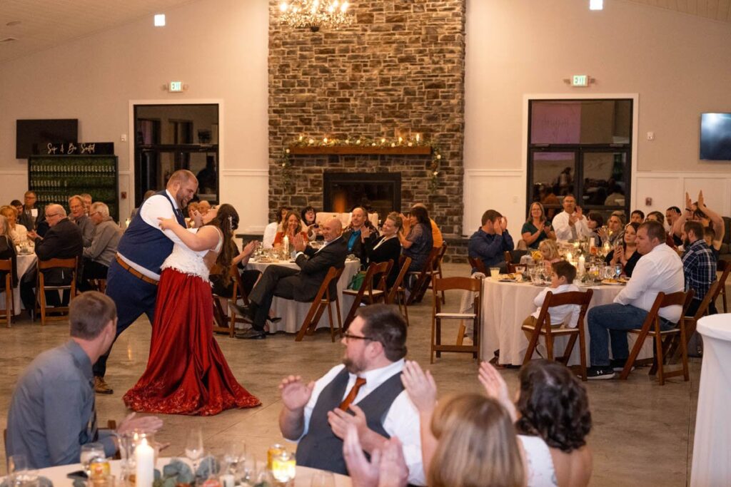 Bride and groom end their first dance with a dip while guests celebrate with them.