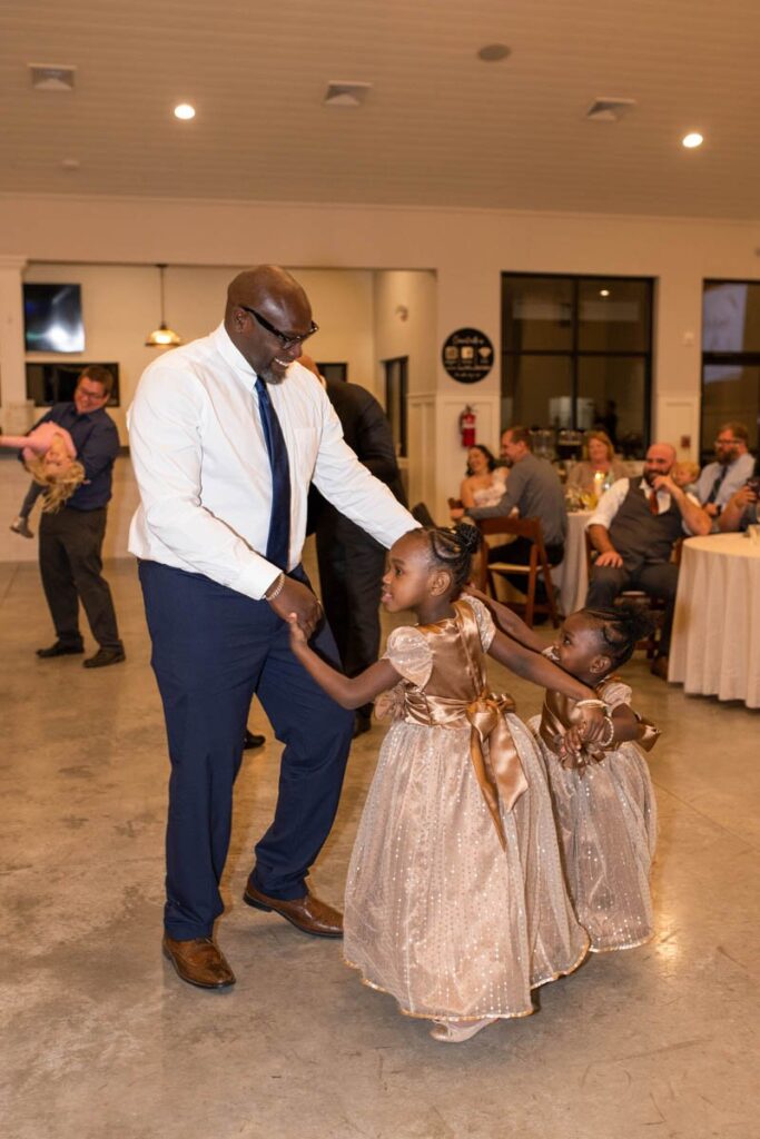 Father dances with his two daughters wearing gold dresses.
