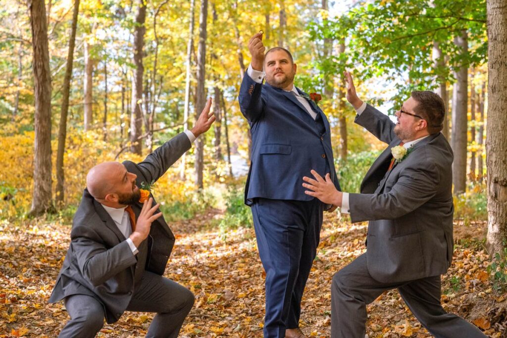 Groom holds up wedding ring and groomsmen stand in awe.