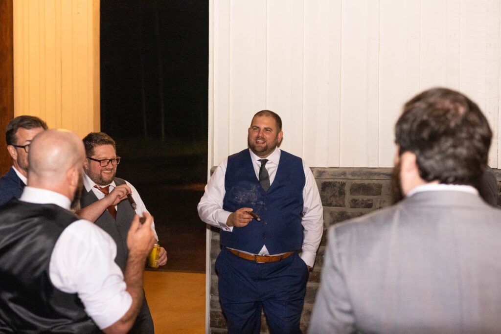 Groom smoking a cigar with the guys after wedding.