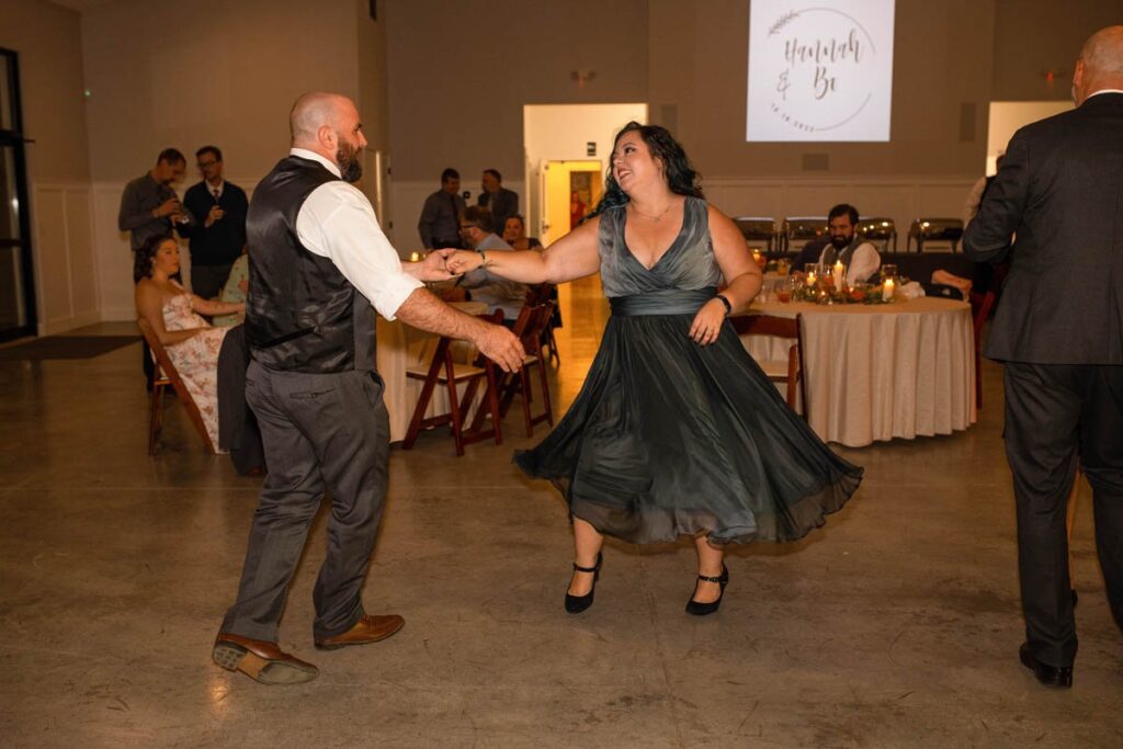 Groomsman dances with wife at wedding reception.