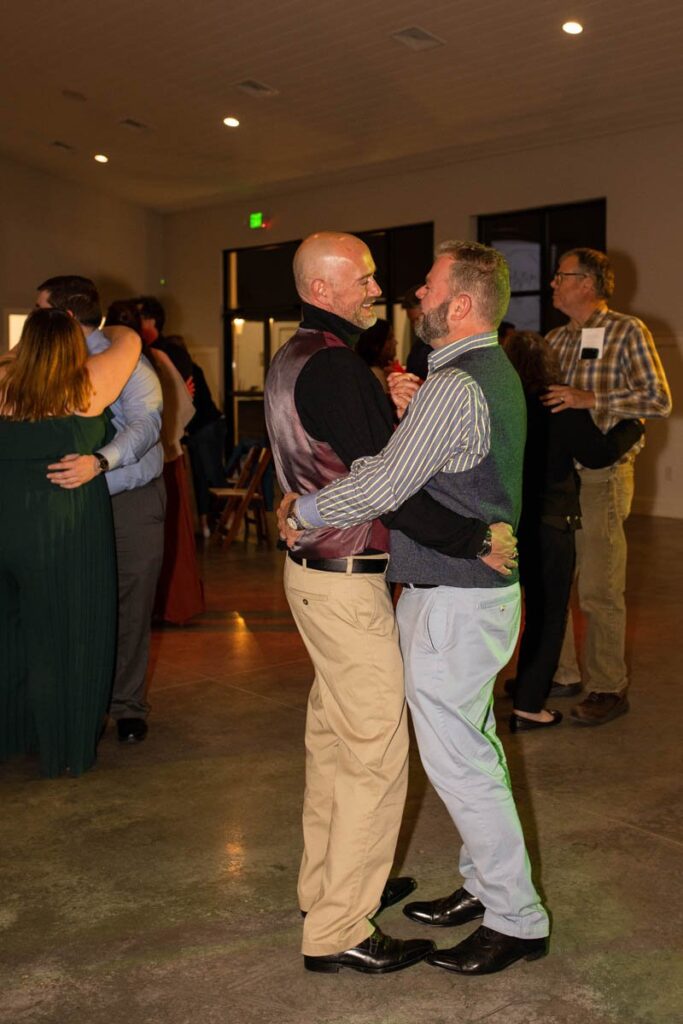 Two men share a dance together at a wedding reception.