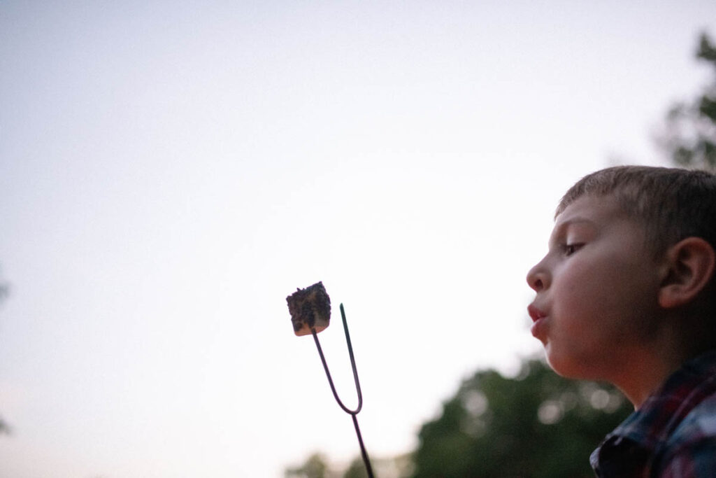 Boy blowing out fire on marshmallow.