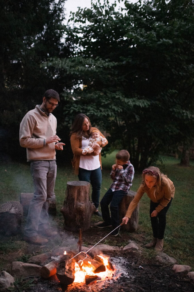 Family makes s'mores together by fire in their backyard.