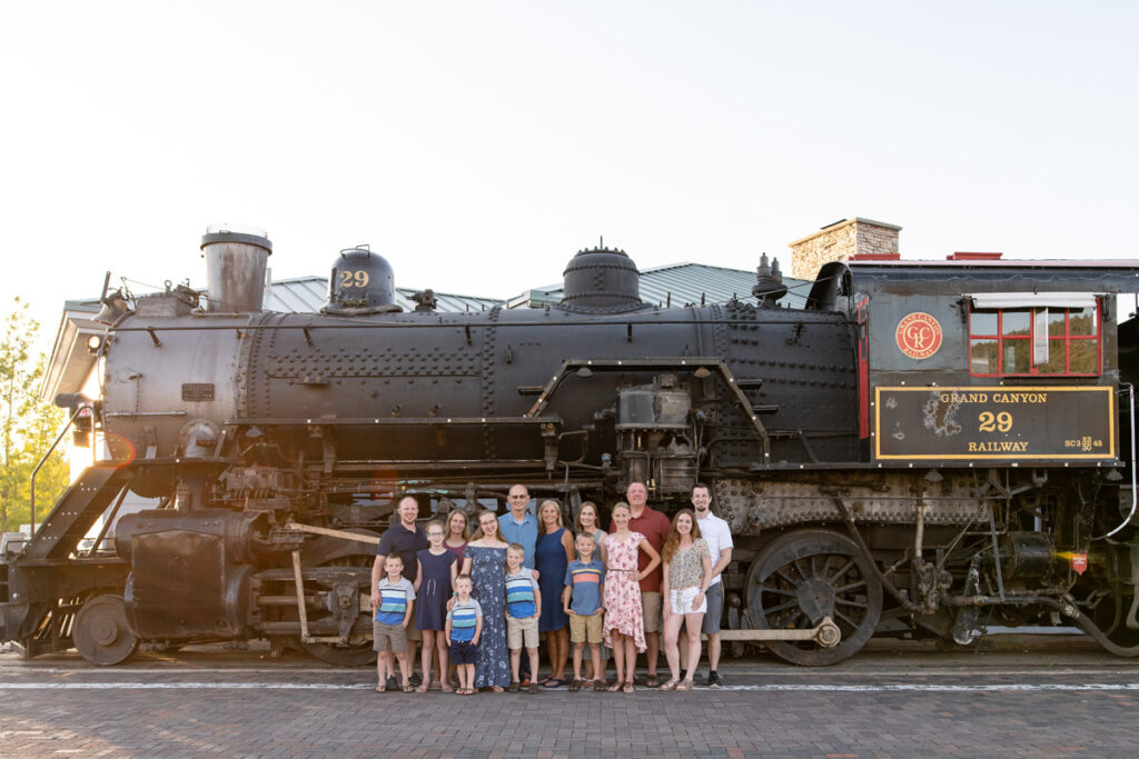 Large family smiles in front of train at Grand Canyon Railway.