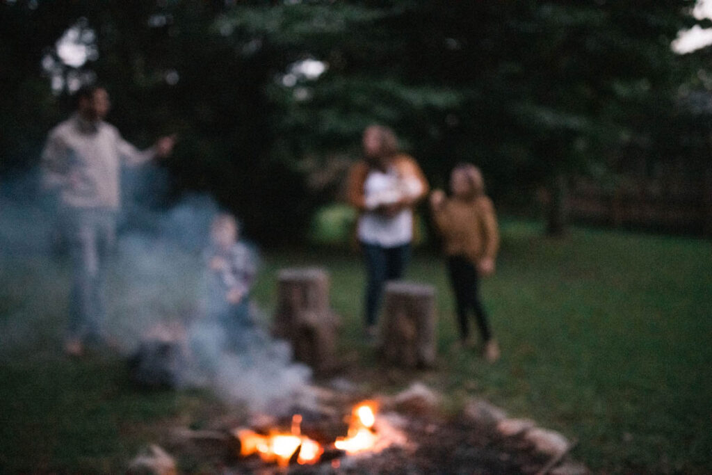 Out of focus image of family gathered around campfire at night.