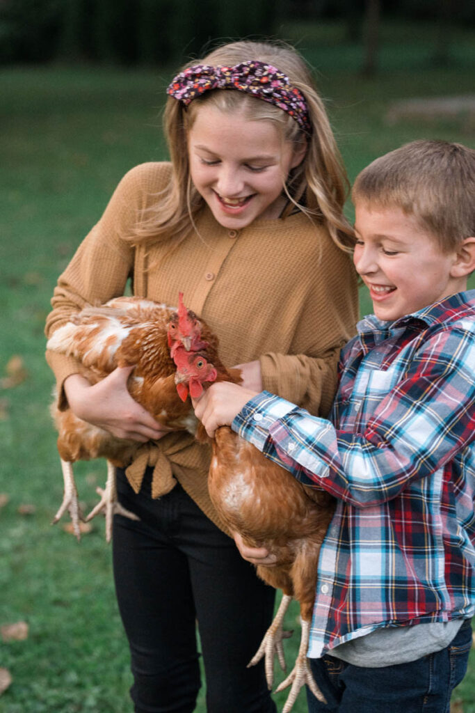 Kids are holding chickens close together and laughing.