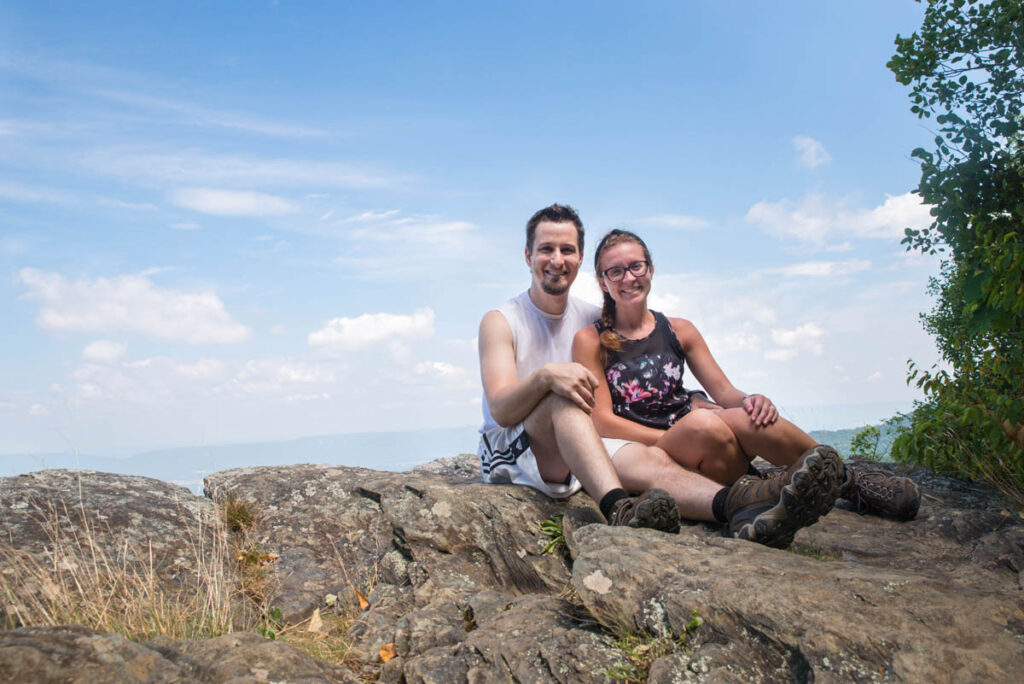 Couple is sitting on a rocky overlook at Shenandoah National Park.