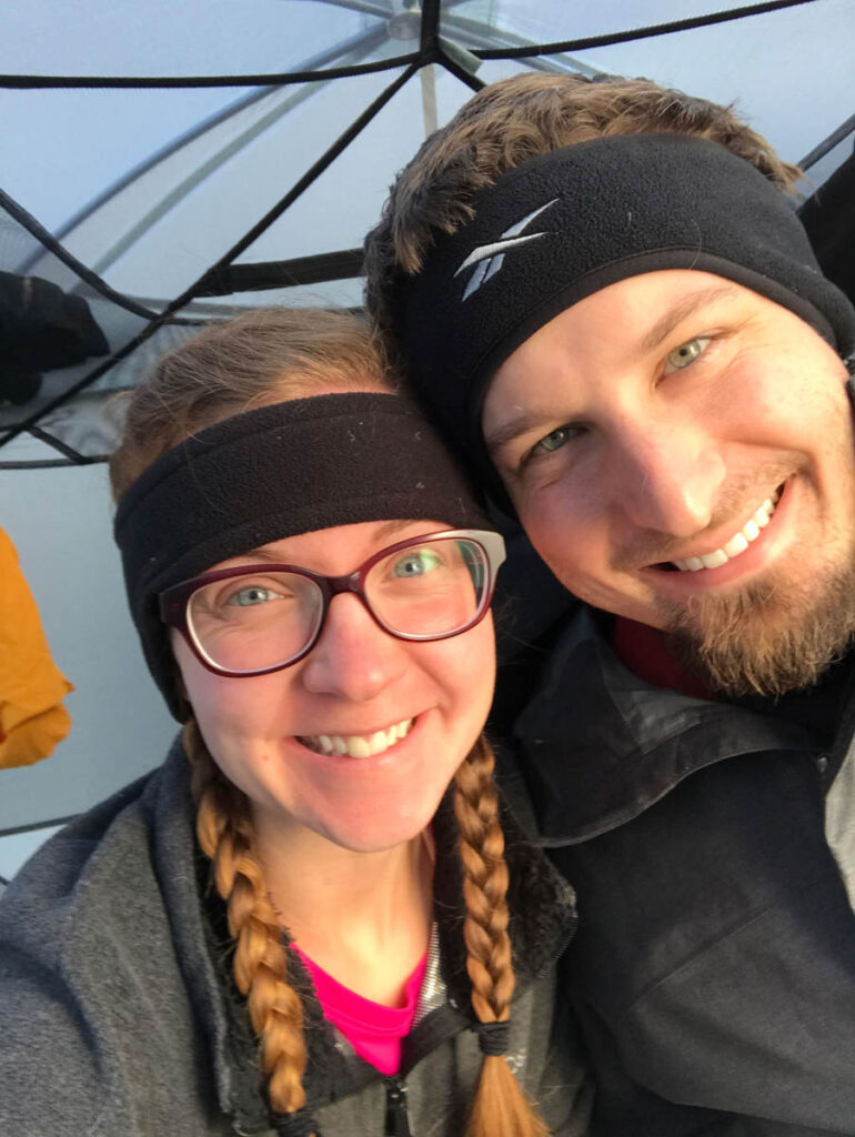 Couple is smiling inside their tent while camping on a backpacking trip.