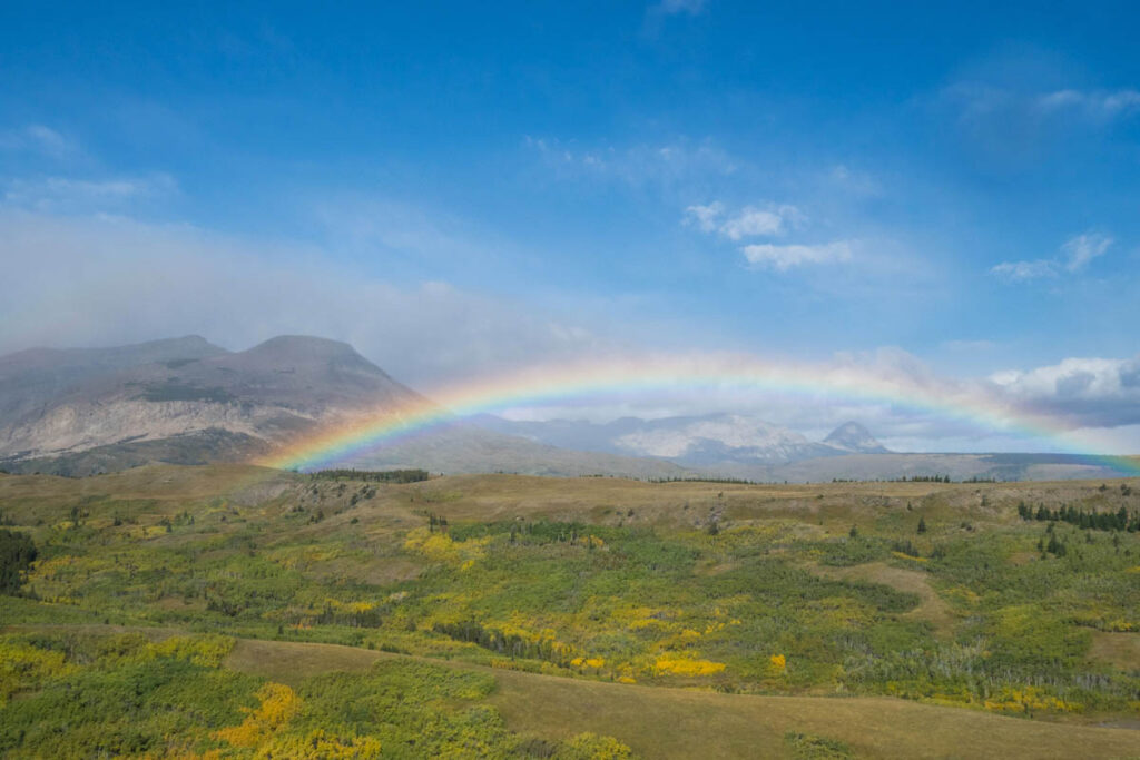 Rainbow in a large valley with mountains in the distance at Glacier National Park.