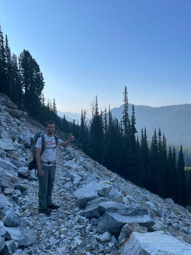 Man gives a thumbs up on rocky trail at sunrise in North Cascades National Park.