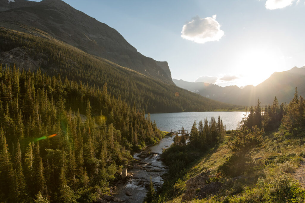 Sun sets over lake trickling into a waterfall at Glacier National Park.