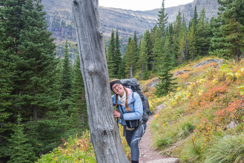 Woman hugs tree while wearing a pack on a hiking trail.
