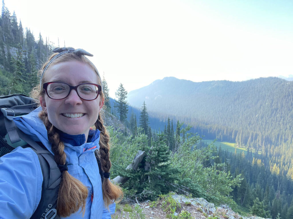 Woman smiles with mountains in the background at North Cascades National Park.