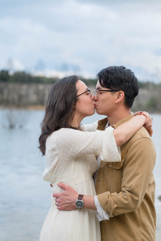 Couple share a kiss in front of a lake at their Midwest elopement.