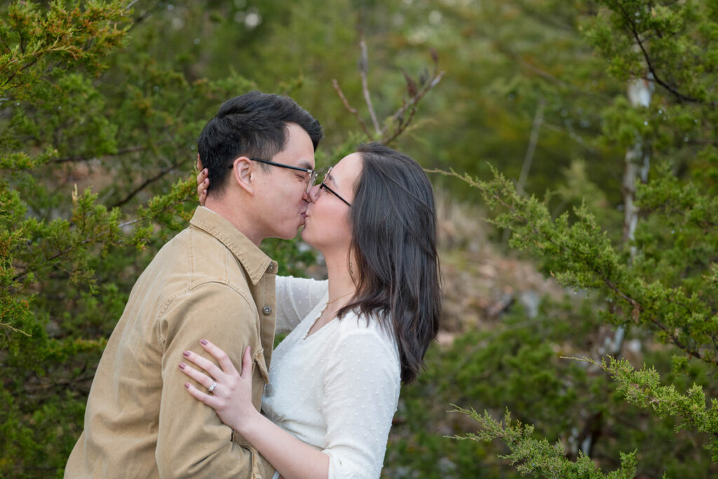 Couple shares a kiss at their Midwest elopement in front of cedar trees.