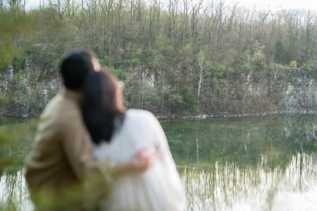 Couple looks at view ahead of them of lake and rocky cliffs.