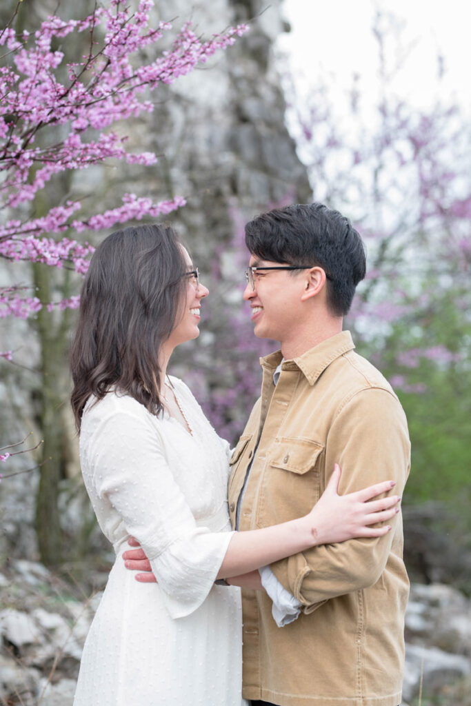 Couple smiling at each other by flowering trees.
