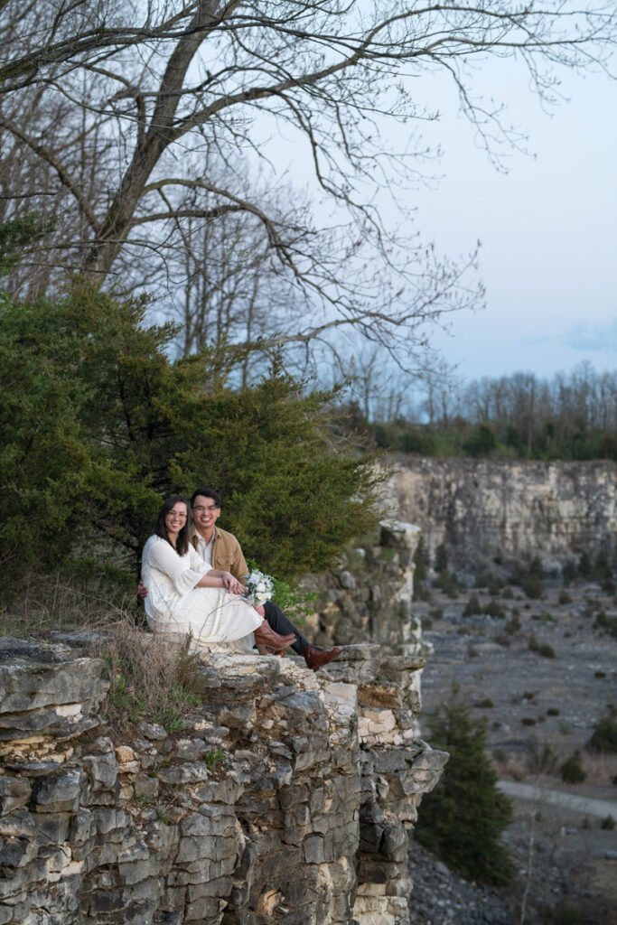 Couple smiling while sitting near cliff.