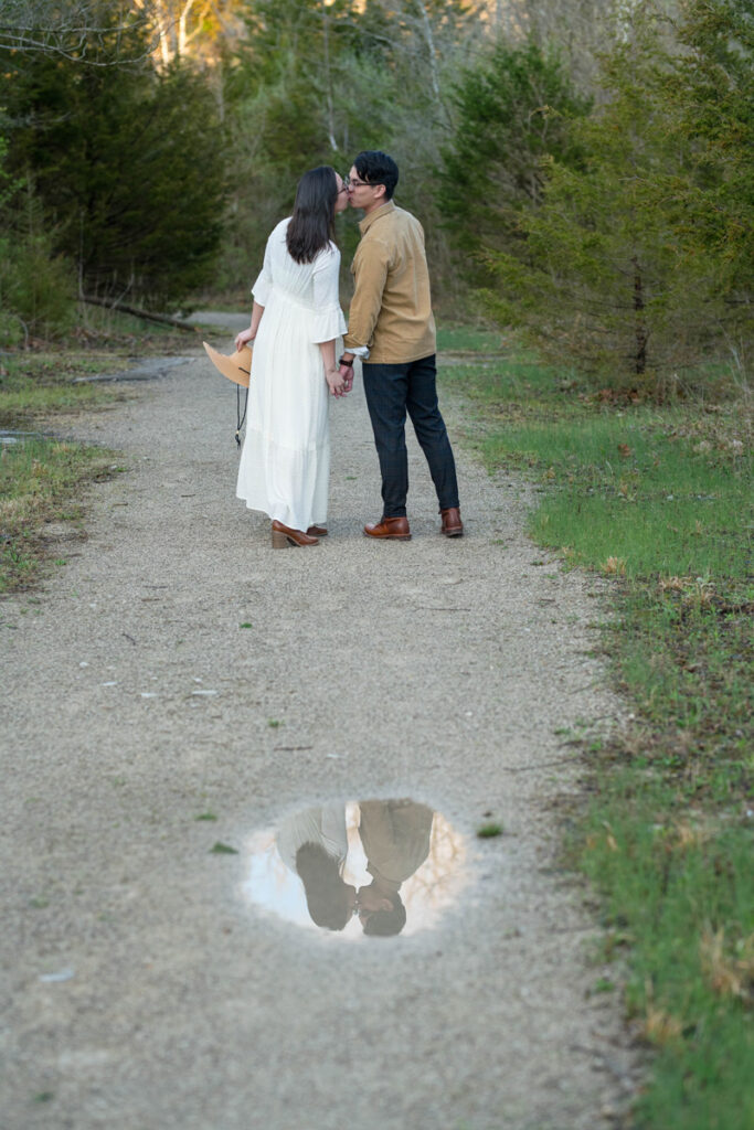 Couple's kiss reflects in a puddle on a trail.