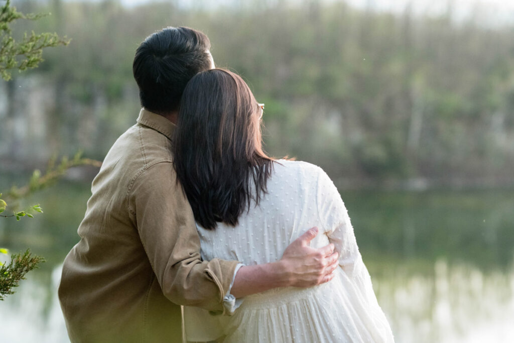 Man holds woman closely while admiring sunset.