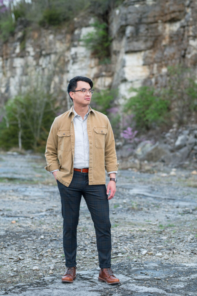 Man looks away while  standing in front of rock wall.