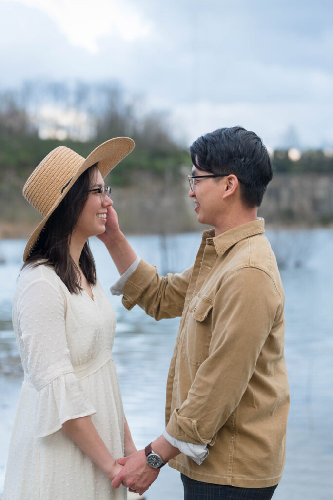 Man tucks woman's hair behind her ear as she smiles at him.