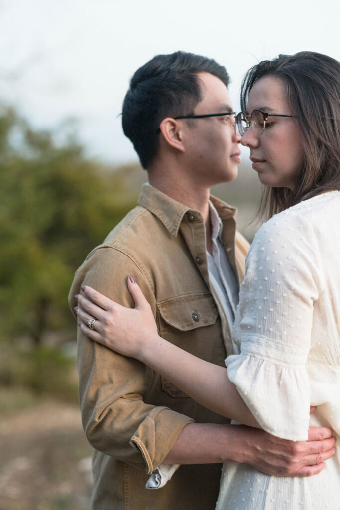 Man and woman embrace while looking away from one another.