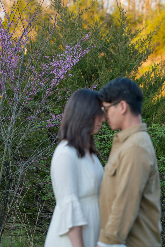 Purple trees in focus behind couple resting their heads together at their Midwest elopement.