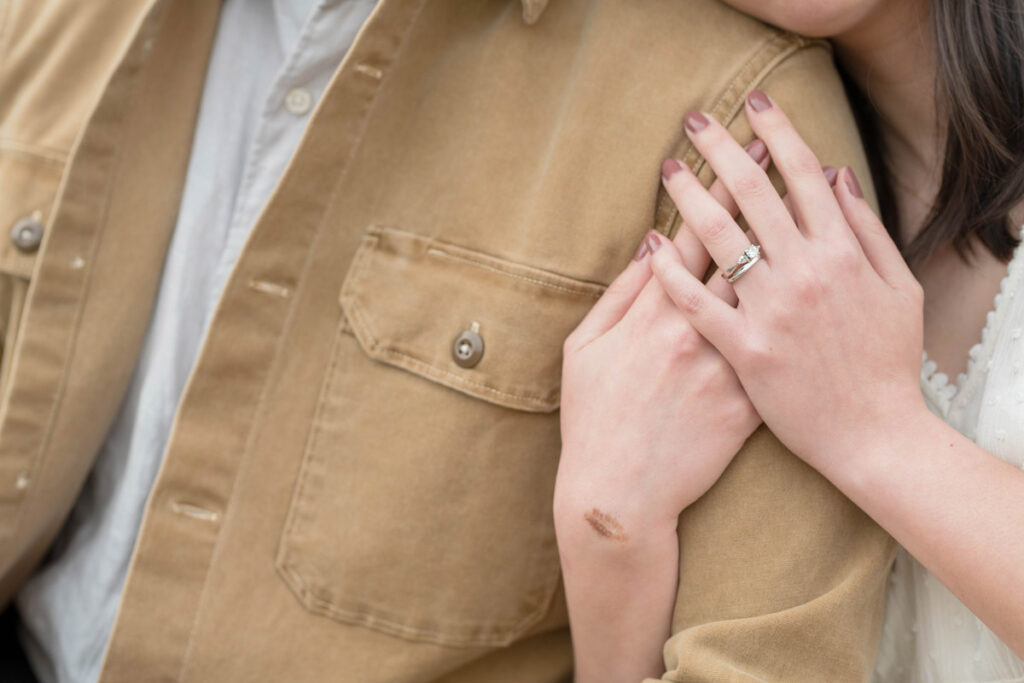 Woman holds onto man's arm showing her wedding rings.