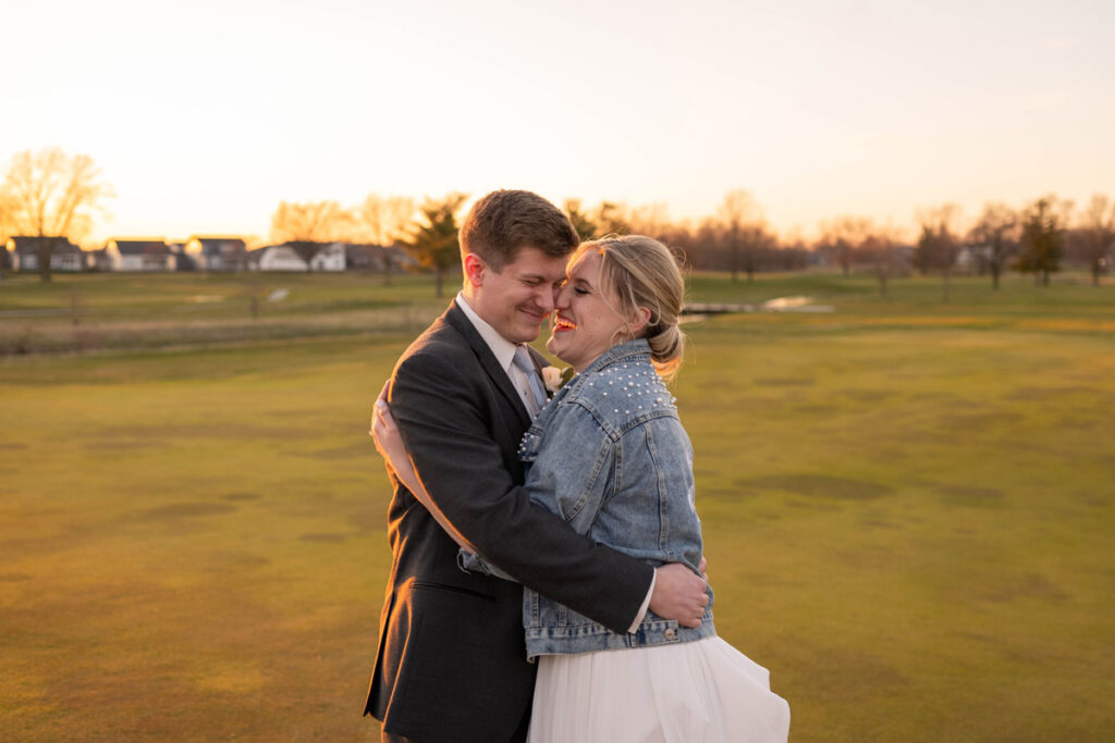 Bride and groom hug and laugh on a golf course near The Cardinal Room.