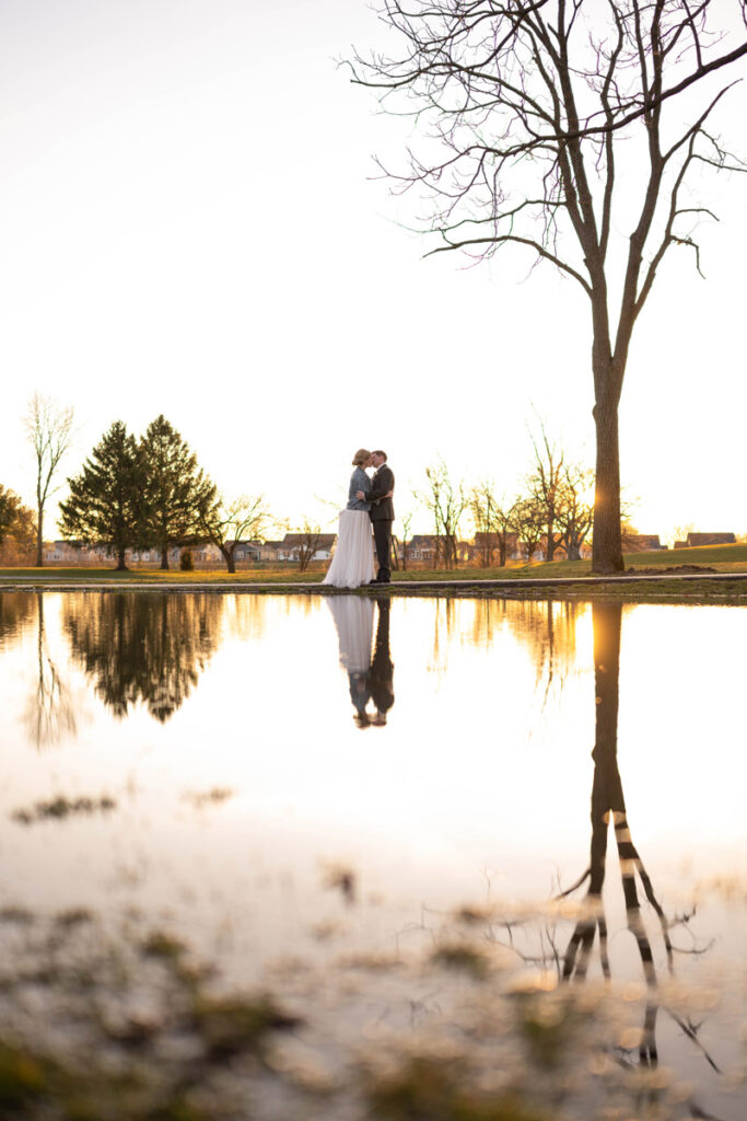 Bride and groom share a kiss with their reflection in a large puddle.