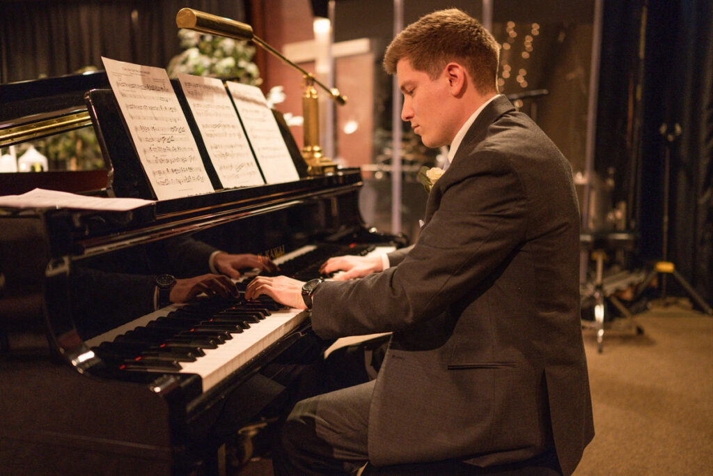 Groom playing piano at the beginning of his own wedding ceremony,