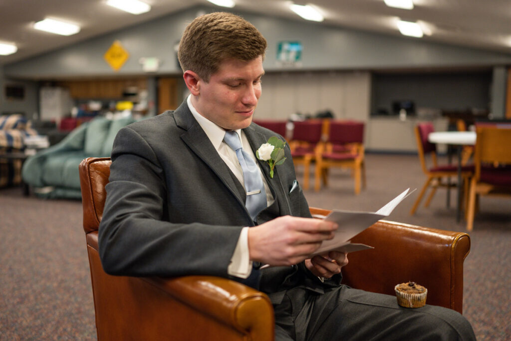 Groom reading love letter from bride and getting teary-eyed.