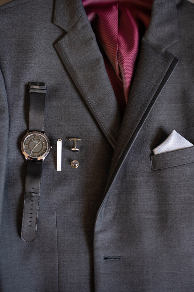 Groom's jacket with his watch, tie clip, and cufflinks.