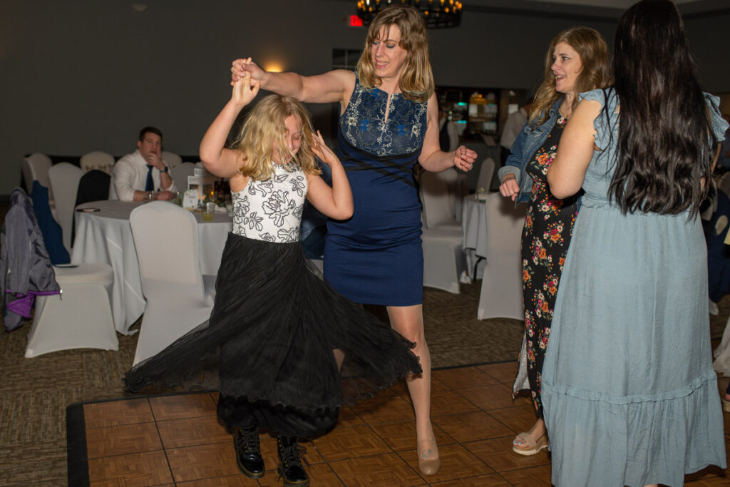 Girl is twirling on dance floor at wedding reception.