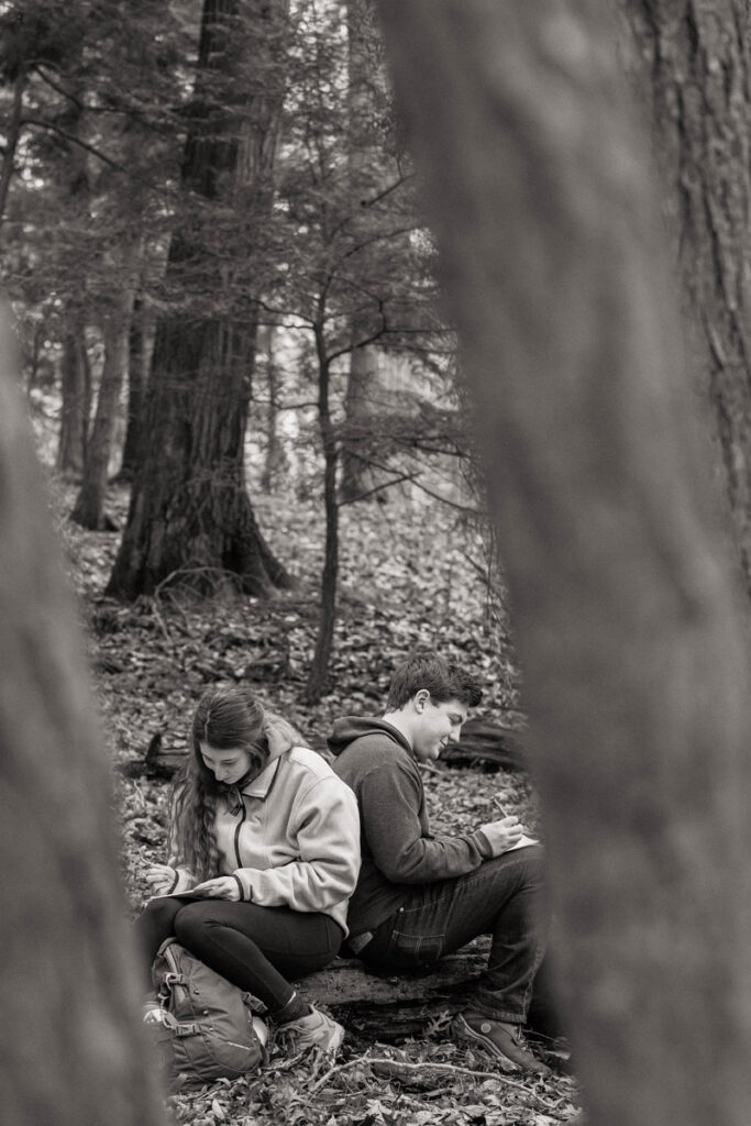 Couple writing vows on a log in the woods.