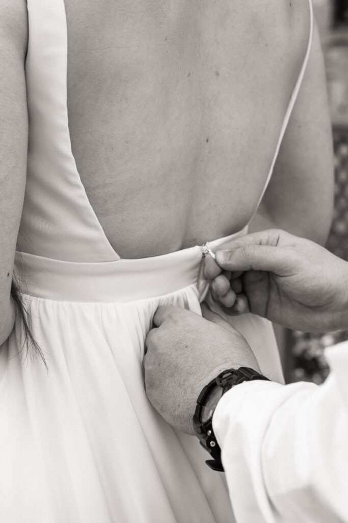 Groom's hands zip up bride's dress.