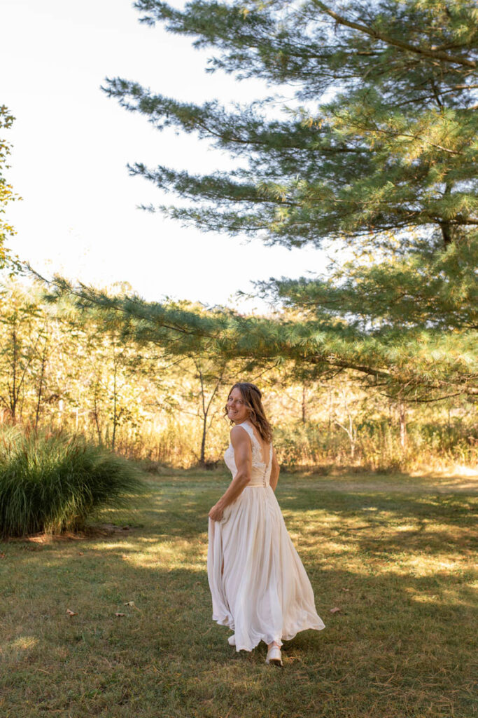 Bride wearing a secondhand dress while running in a field.