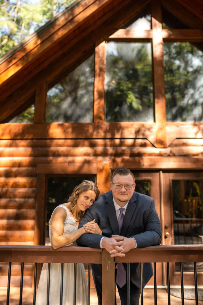 Bride and groom standing in front of a-frame cabin.