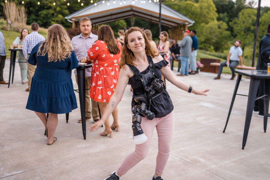 Female photographer dances at outdoor wedding reception.