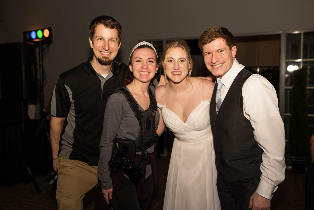 Bride and groom smile for a photo with their wedding photo and video team.