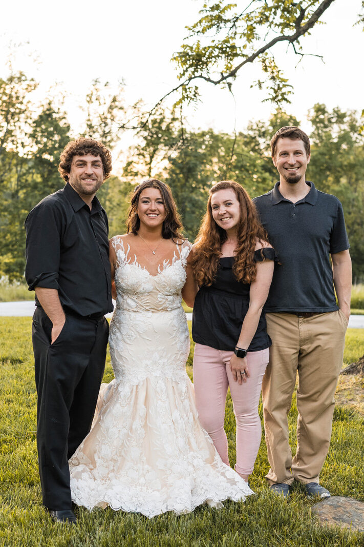 Couple smiles with photographers at their wedding.