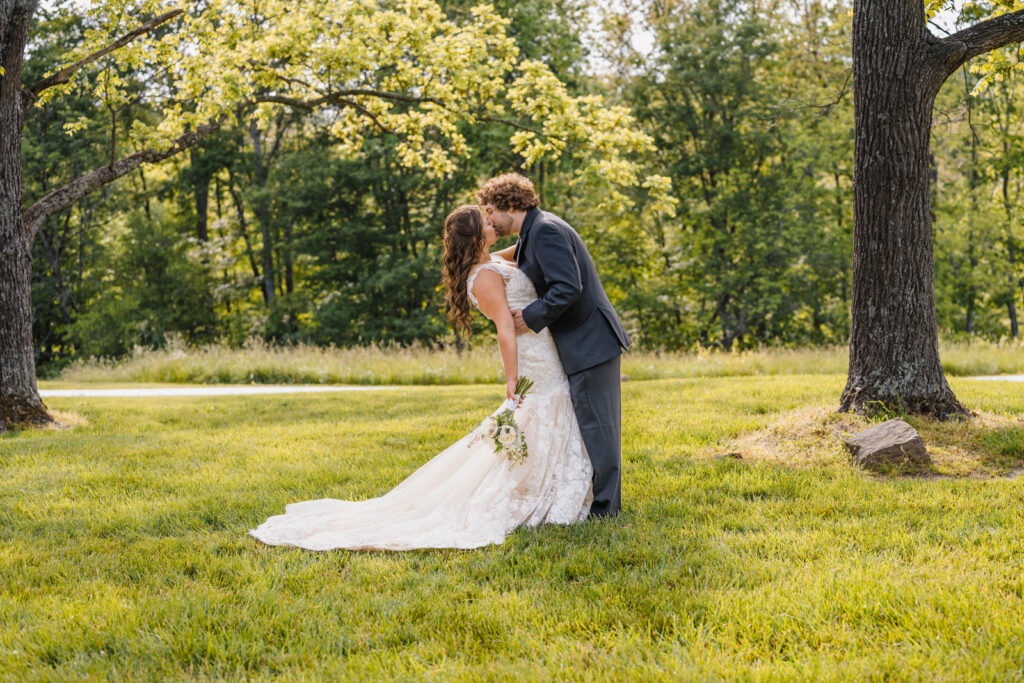 Bride and groom share a kiss among the trees.