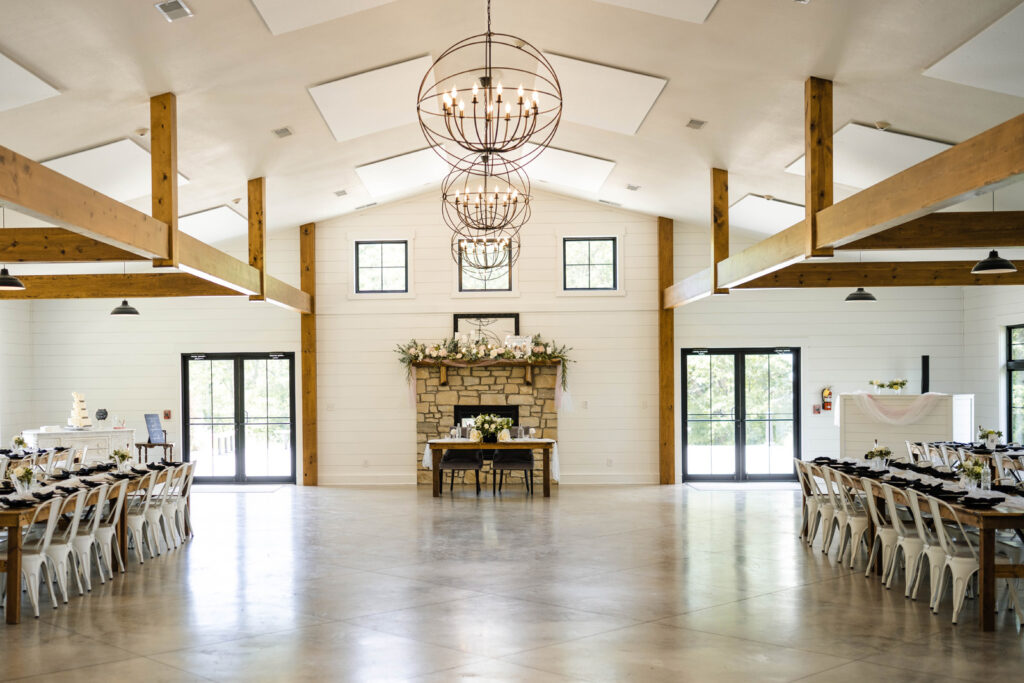 The reception area at The Wilds Wedding Venue consists of large wooden tables, a fireplace with a sweetheart's table, and an open dance floor.