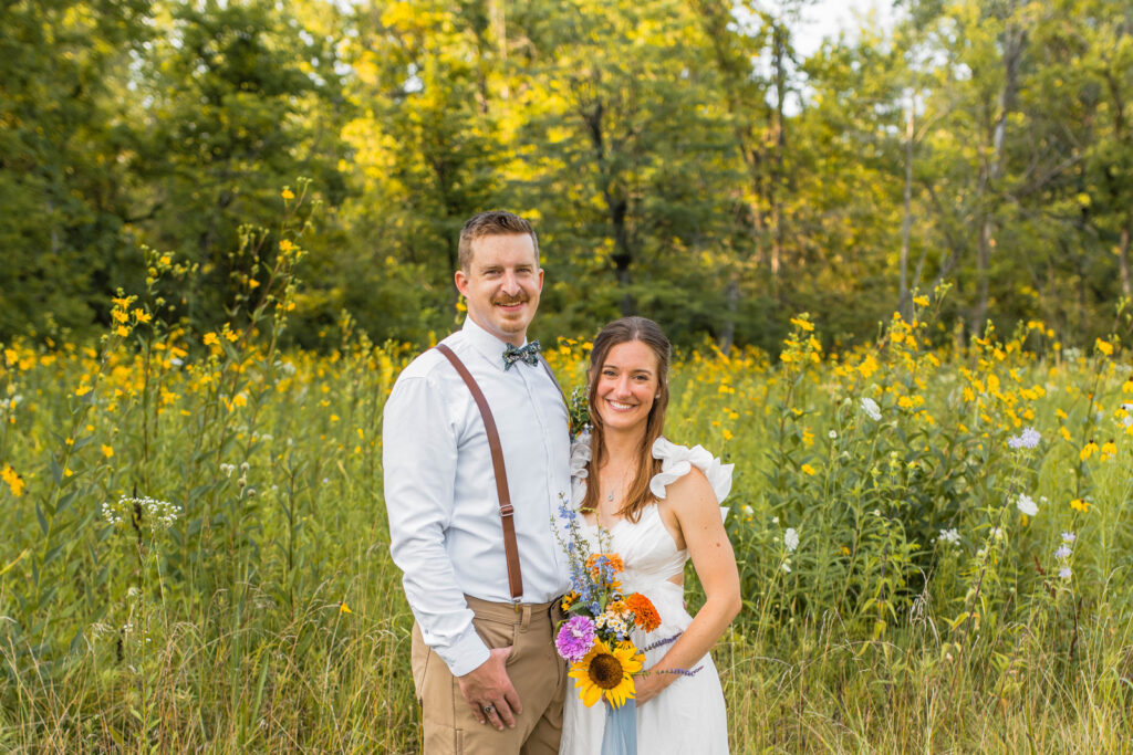 Bride and groom smiling at their wildflower elopement in front of a field of wildflowers at Eagle Creek Park.