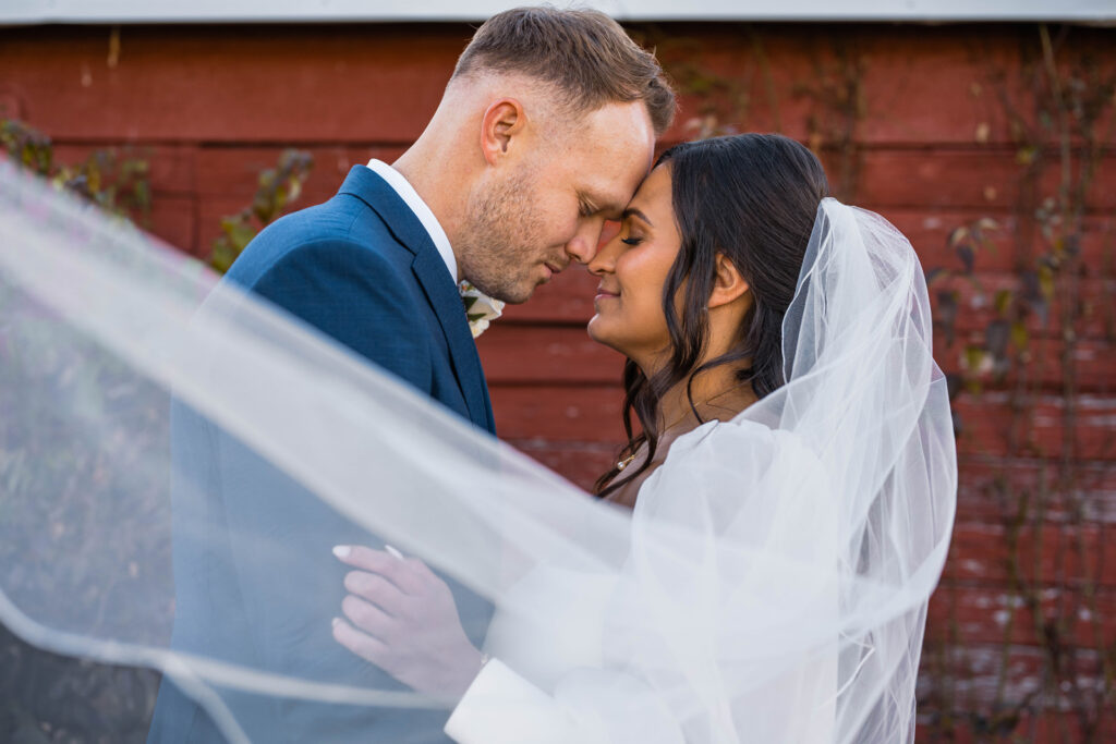 Bride and groom rest their heads together and smile.