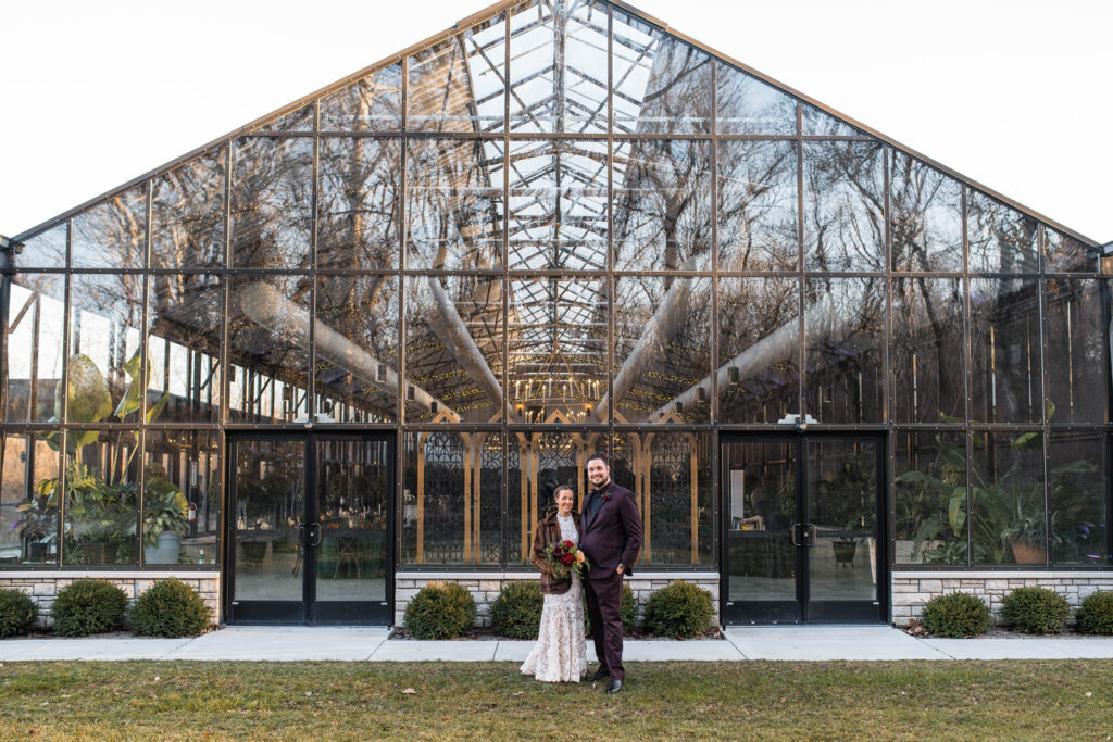 Bride and Groom standing next to glass conservatory at The Conservatory at Evergreen.