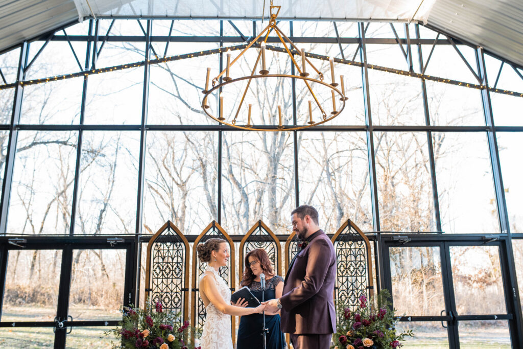 Bride and groom exchanging their vows during an indoor ceremony at The Conservatory at Evergreen.