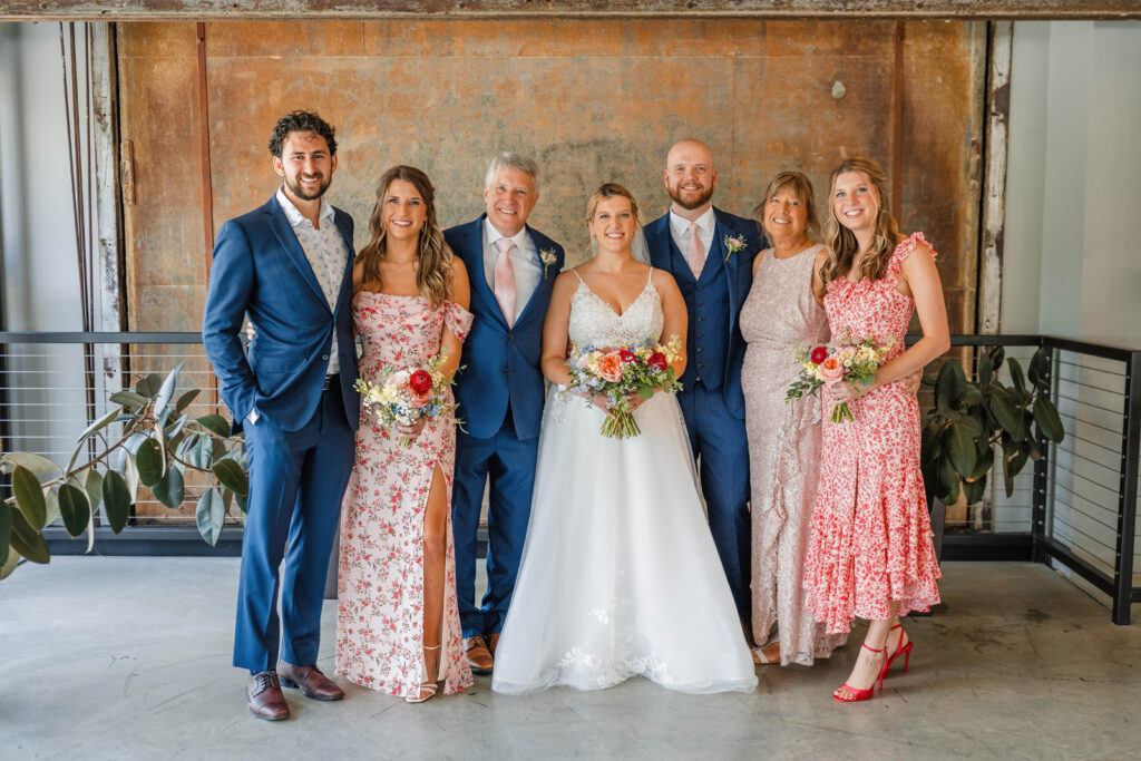 Bride and groom smiling with family in mezzanine at One World at Woolery Mill.